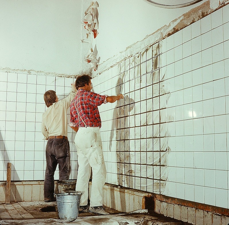 A craftsman working on a wall surface during a kitchen renovation