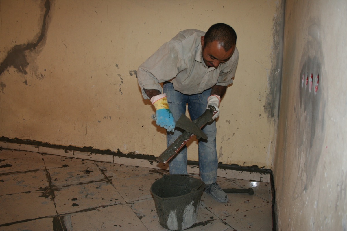 A professional tiler laying ceramic floor tiles using careful precision and technique