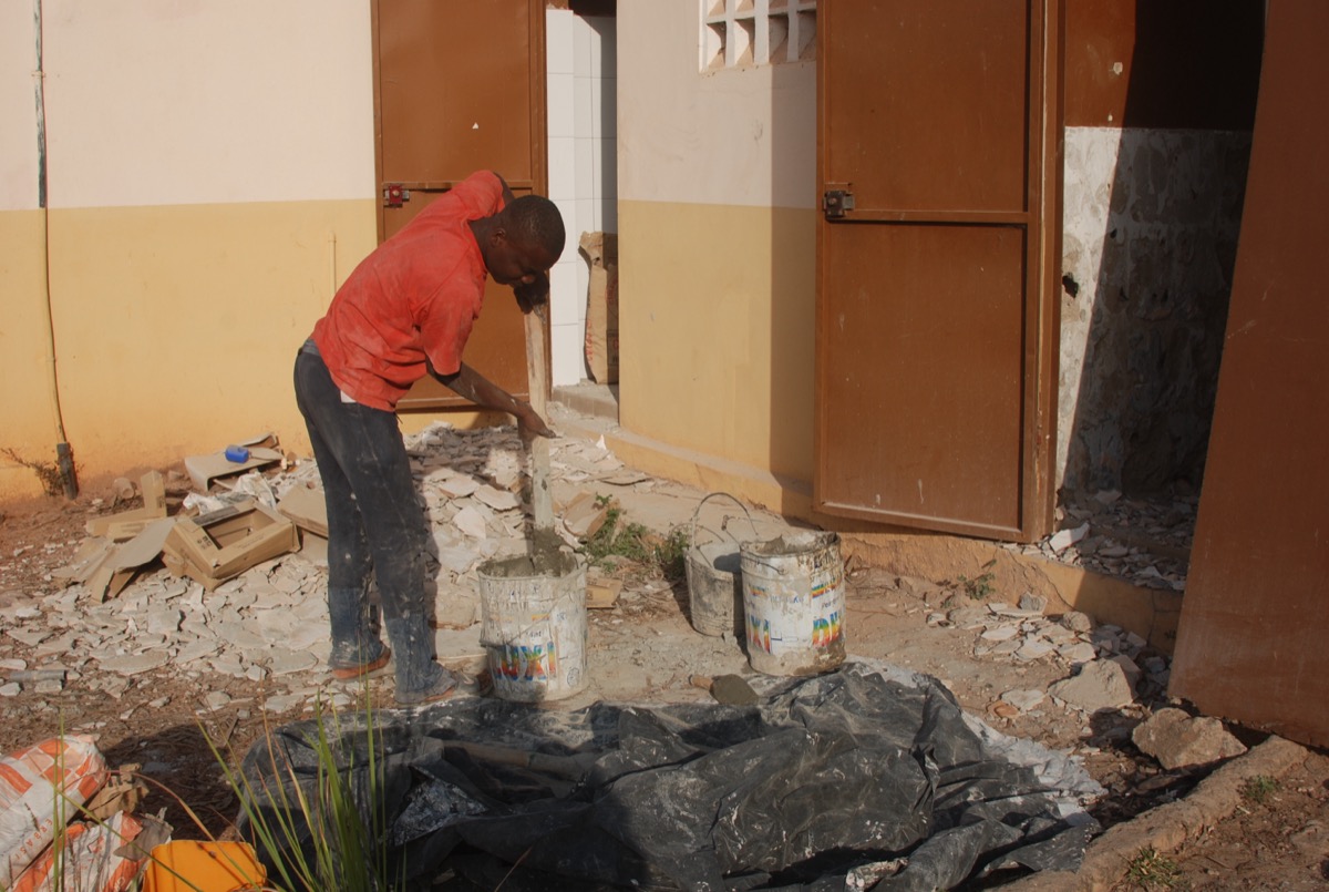 A professional tile layer working on a wall surface checking for plumb