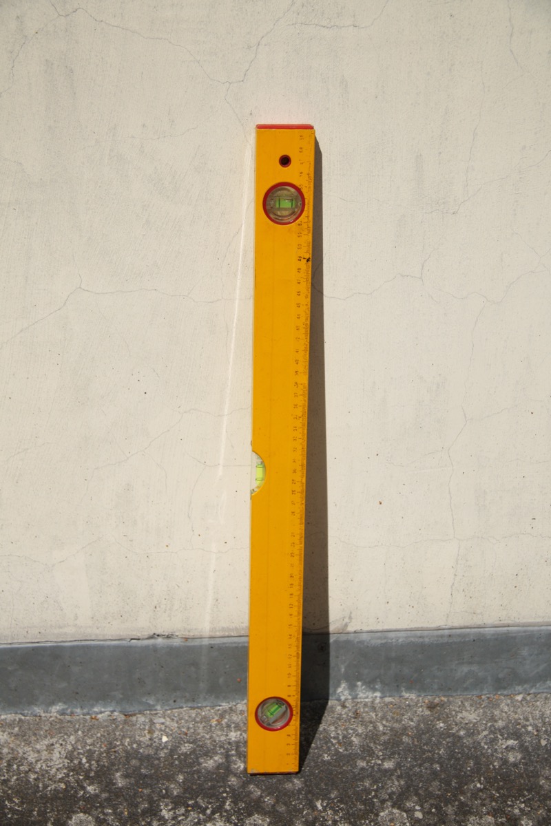 A spirit level tool photographed in use showing how to read the bubble vial